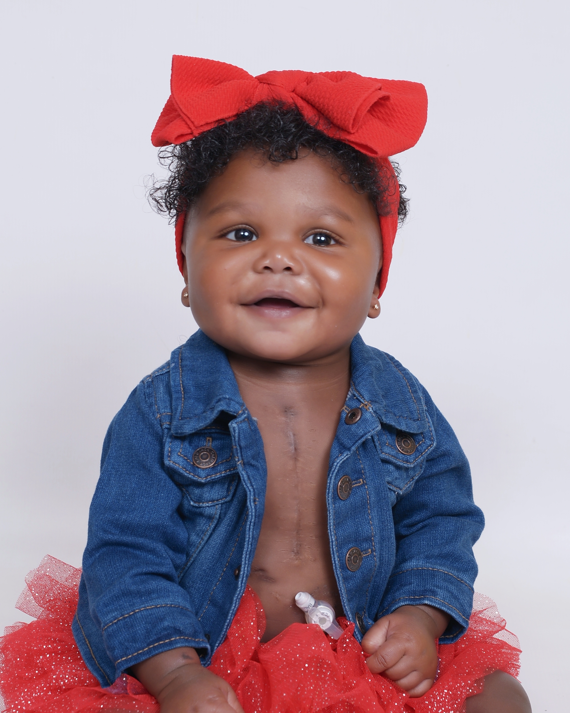 Rielle smiling with a red bow tie on her head