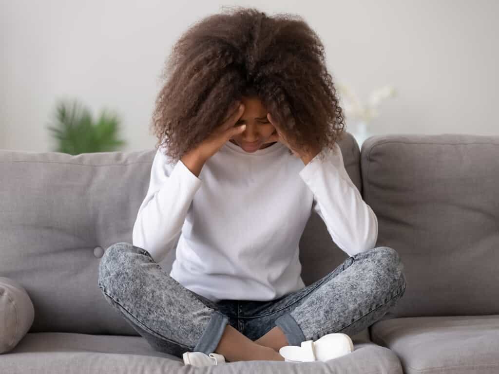 young girl holding head and looking down 