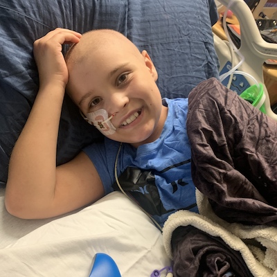 smiling child cancer patient in hospital bed