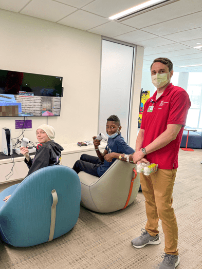 Two teenage boys playing video games with a man who is volunteering