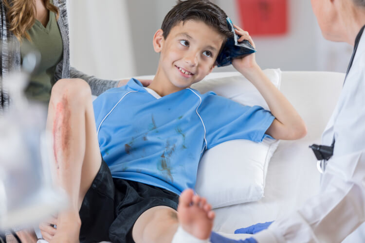 Injured young boy soccer player holds ice pack on his head