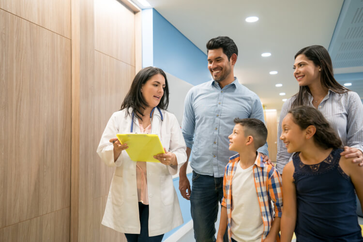 Female doctor talking to patient while his family is listening and smiling