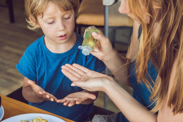 child and mother applying hand sanitizer 