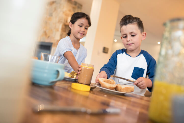 two children spreading peanut butter on toast