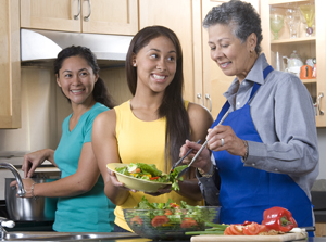 Three women in kitchen making a meal.